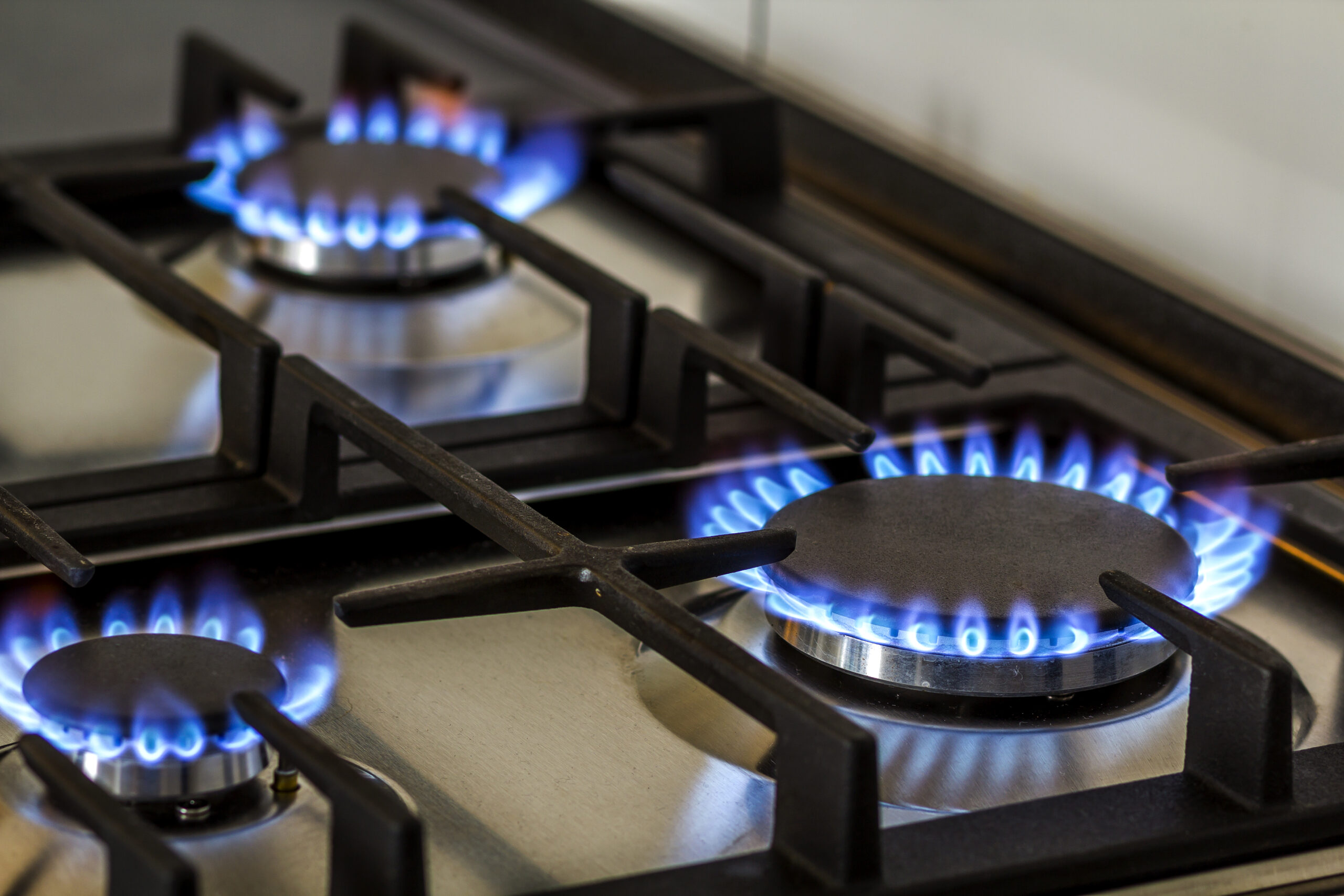 Natural gas burning on kitchen gas stove in the dark. Panel from steel with a gas ring burner on a black background, close-up shooting.